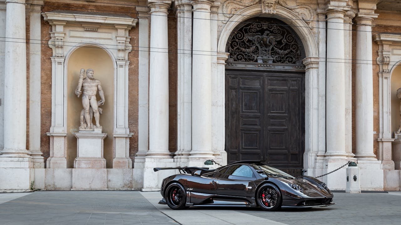 Stunning hypercar parked in front of grand architectural building with classical statues.