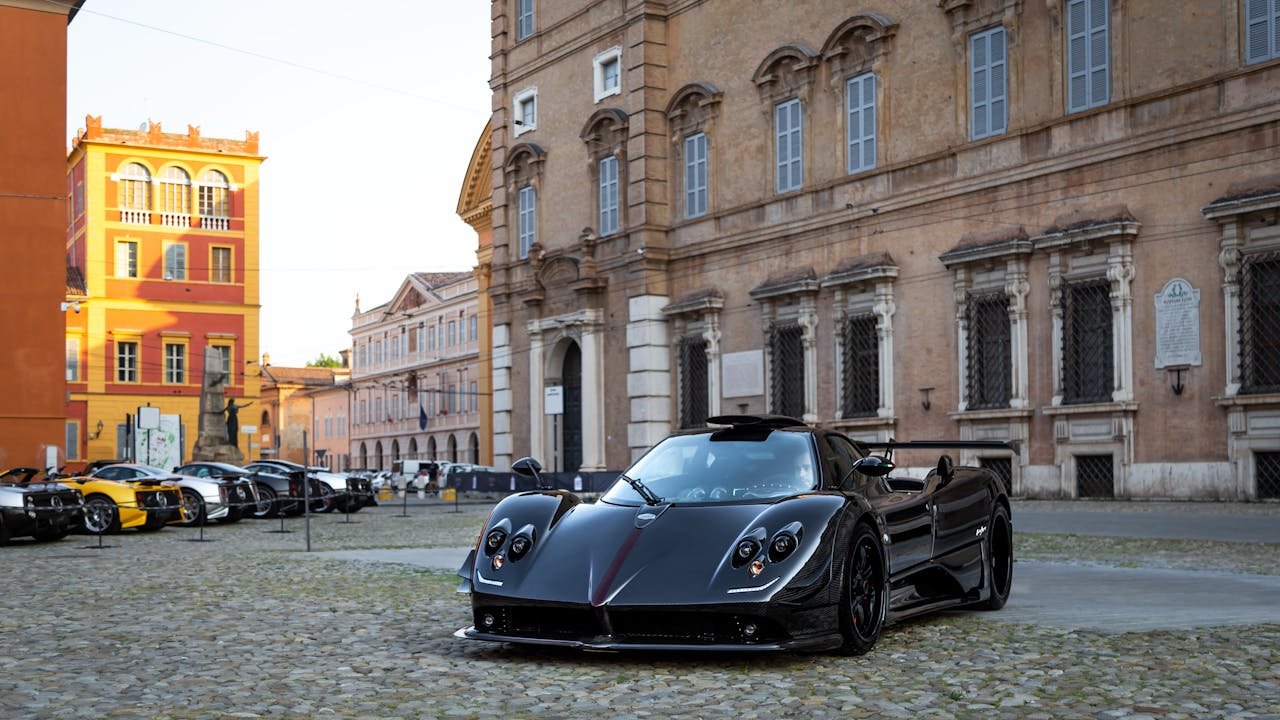 Black supercar parked in a historic European city plaza, exuding luxury and style.